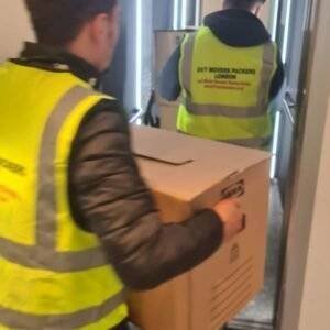 two mans wearing jackets of 24/7 movers packers london carrying boxes from a home and providing removal services
