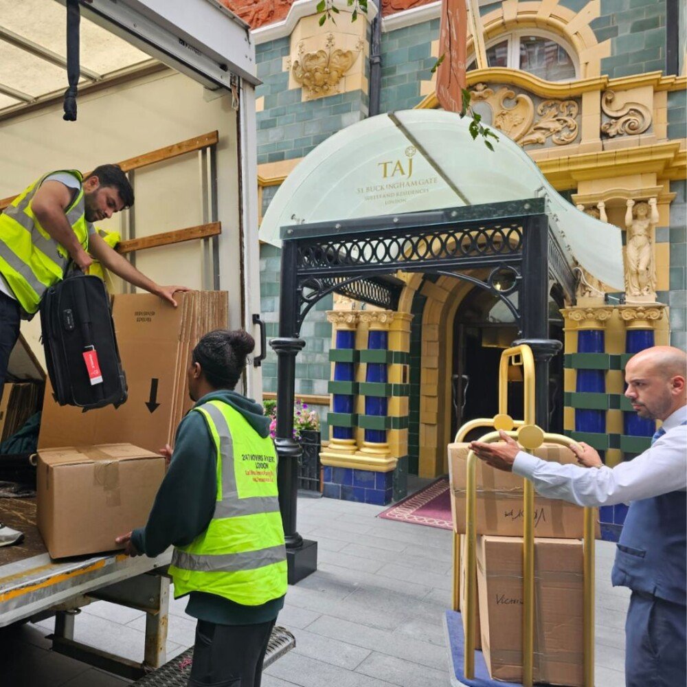Two workers of 24/7 Movers Packers London are loading packed boxes into moving trolleys